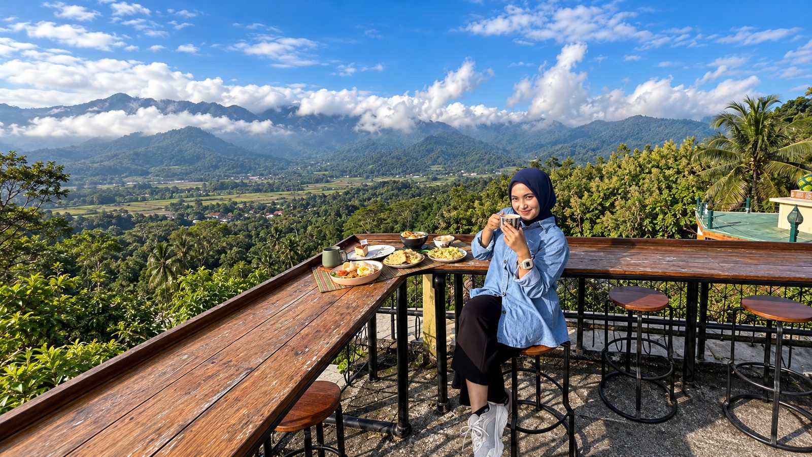 Pengunjung duduk di meja kayu menghadap lembah dan Perbukitan Menoreh di bawah langit cerah
