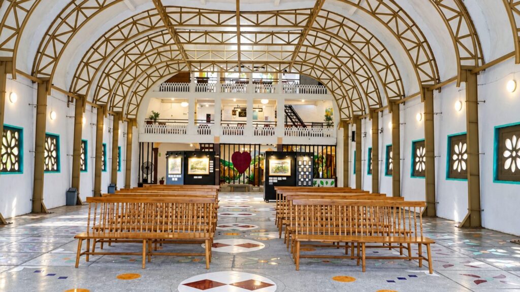 Wisata religi Magelang: ruang dalam Rumah Doa Bukit Rhema dengan bangku kayu dan rangka atap melengkung