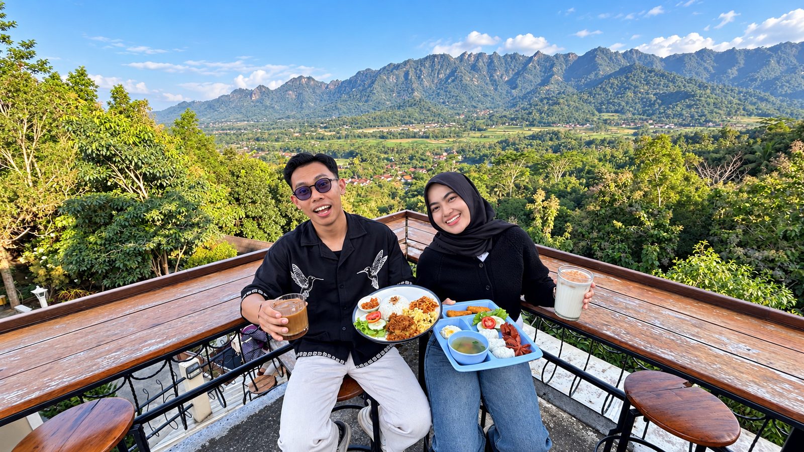 Dua pengunjung menikmati makanan dan minuman di meja kayu dengan latar Perbukitan Menoreh